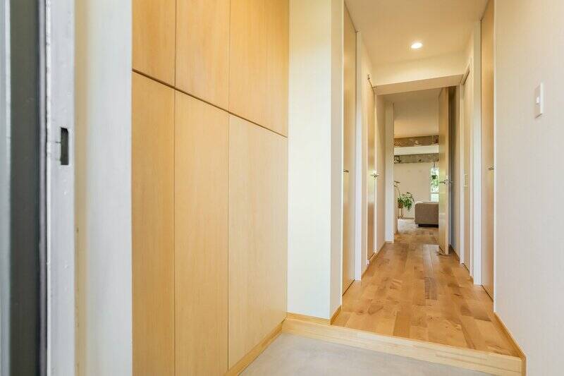 玄関ドアを開けると、大容量の下足入れを備えた玄関土間が。木の温もりとモルタルの素材感がたまりませんね〜。