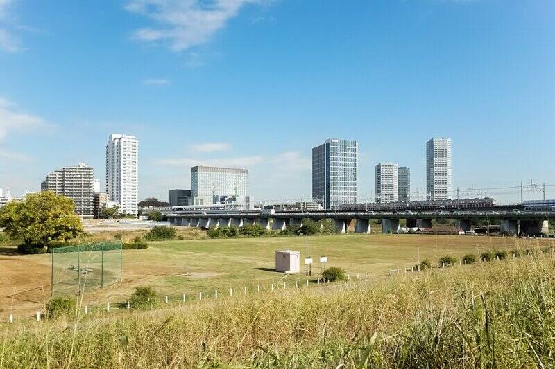 多摩川緑地の広大な野球場越しに<b>「二子玉川」駅</b>を眺めたところ。<b>マンションから河川敷までは徒歩６分</b>。ご近所に自然も賑わいもある立地、いいですね！