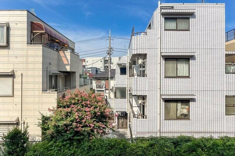 ２階に所在している本住戸。建物の間から空が顔を覗かせています。