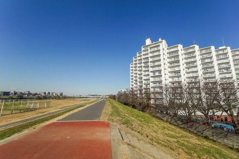 今回の物件は、多摩川河川敷沿いに位置する７階の角住戸（なんと４面角）！ 右手で光を受けている真っ白なバルコニーのどれかが、お目当て住戸かと思うとワクワクしちゃいますね。