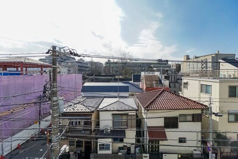 窓の外に出ると、こちらの住戸が正面の住宅や電線よりも背が高いのがわかります。気持ちよく開けた空が見えて、なかなか爽快です！ 左手のピンク色の多いのある建設現場は、2025年1月末まで工事中とのこと。