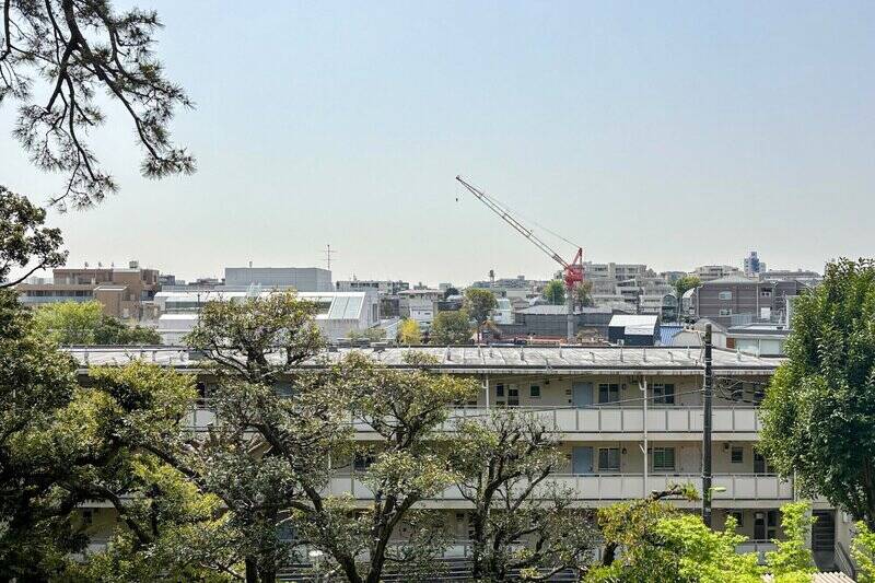住戸が所在するのは5階部分。周囲の建物より頭ひとつ高い位置で、敷地を囲う木々越しに街並みと空が見渡せます。