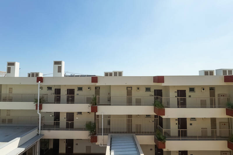 視界の半分は青空、もう半分には低層棟の共用廊下が見えます。渡り廊下分の距離は取れていますが、少し視線が気になるかも。等間隔に並ぶ花台が、かわいらしいですね。