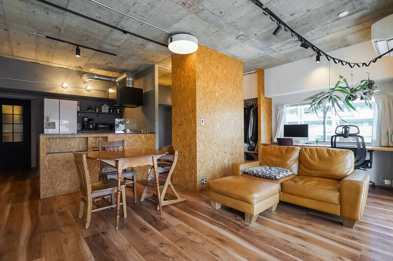 LDKの広さは約19帖。写真中央のOSB材の壁で、LDKと洋室がゆるやかに仕切られた1LDKの間取り。木片をプレスしたOSBボードや躯体現し仕上げの天井など、クラフト感ある内装です。