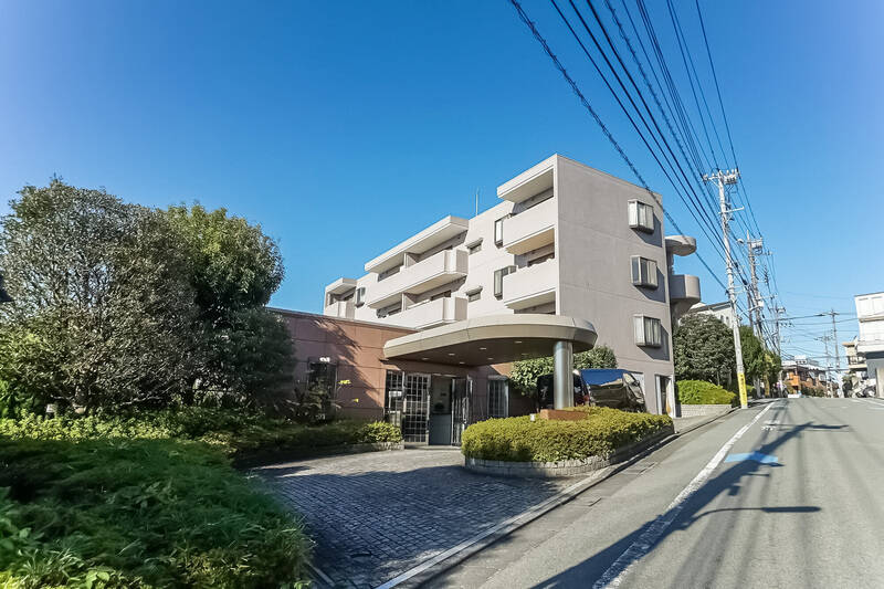 1990年築、総戸数14戸のマンション。エントランス上部の丸い庇(ひさし)が目印です。坂道に建っているため、エントランスは3階に相当します。