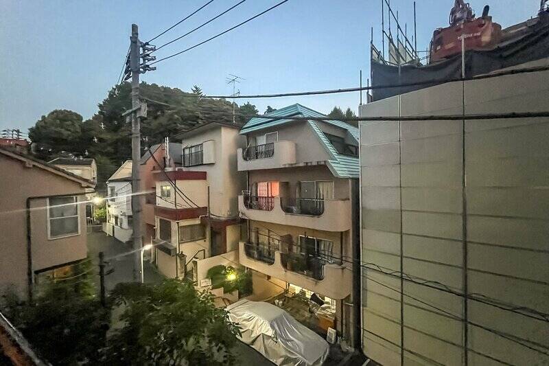 洋室Aからアクセスする南西向きのバルコニーからの眺望(やや左手を向いています)。まわりはほとんどが住宅で、すぐ近くにある「代々木八幡宮」の緑も見えます。日没後に撮影したため、写真はやや暗めに写っています。