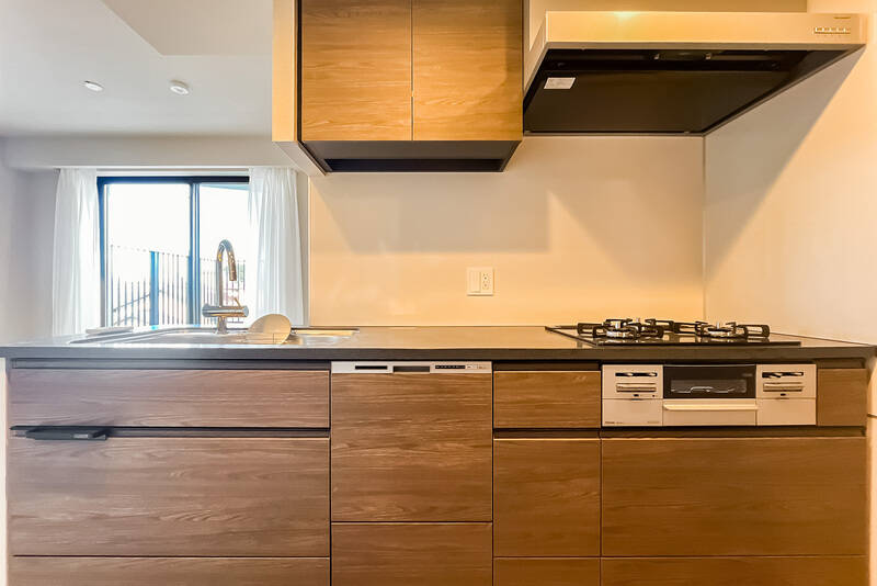 <p>キッチンは3口コンロタイプで、食洗機を完備。背面には冷蔵庫置き場とカップボードを置けるスペースを確保しています。</p>