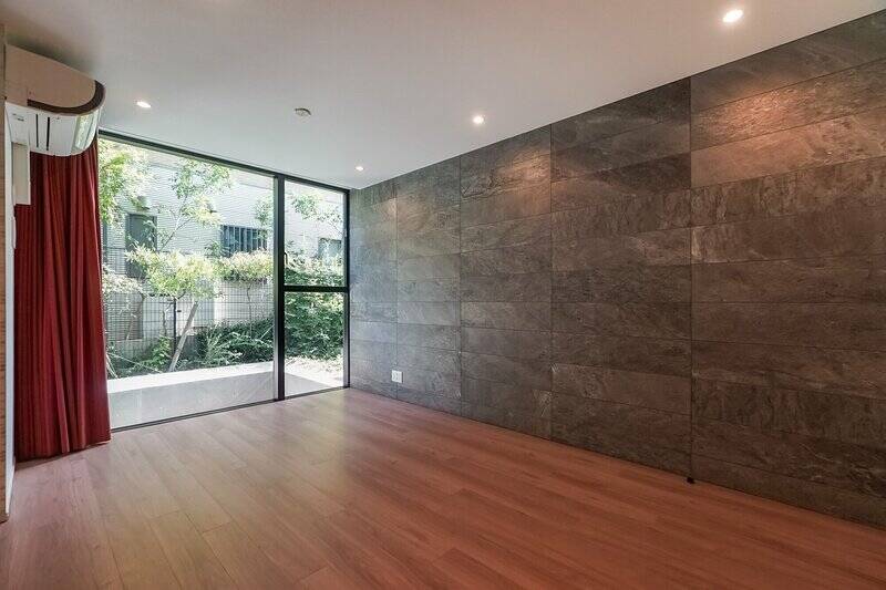 ドアを開ければ、そこは約14帖のLDK。東側がガラス張りになっており、まるで外につながっているような開放感です。右手の壁にはダークグレーのタイルを貼り、大人の空間らしく仕上げています。