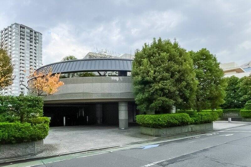 野村不動産分譲、竹中工務店施工により1991年に竣工。美しく剪定された木々や石畳の車寄せ、弧を描く外観で一見美術館のようですが、敷地は奥に長く、「白金二丁目第二緑地」と寄り添うように建っています。