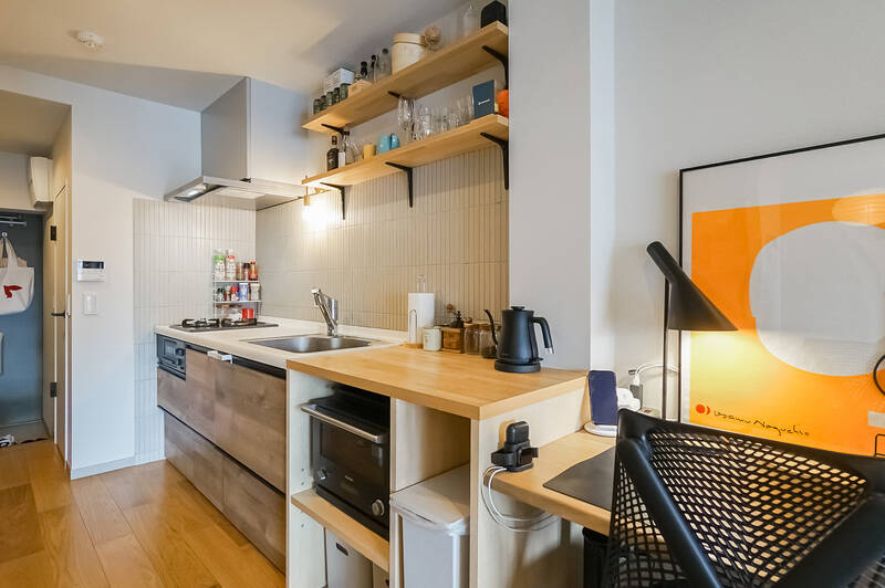 細長いタイルがあしらわれた壁付けのキッチン。造作の棚で作業スペースが延長されており、二人で並んで料理することも◎