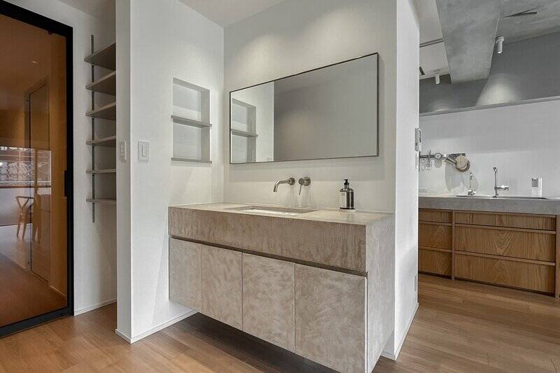 キッチンと同じモールテックス仕上げで、壁付混合水栓やミラーの縁がアクセント。