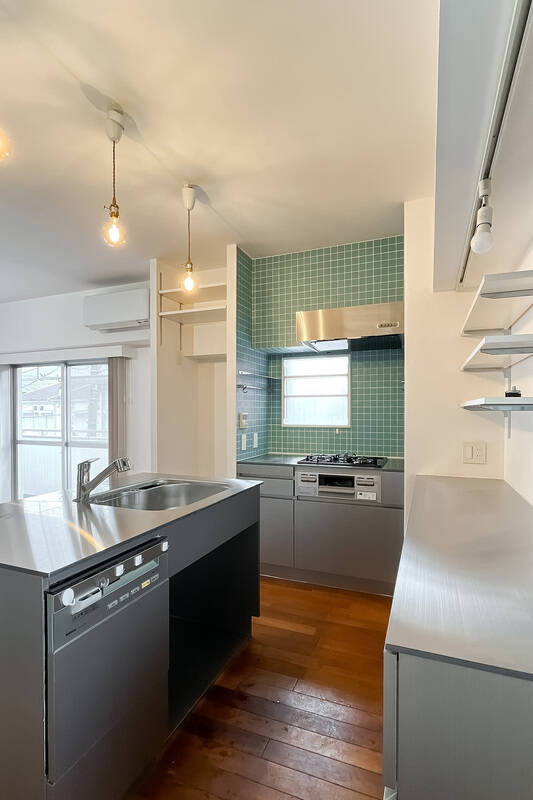 キッチンはシンクを中心に、壁付けのコンロとカップボードを配置したゆとりのある造り。天板にはステンレスを採用しています。