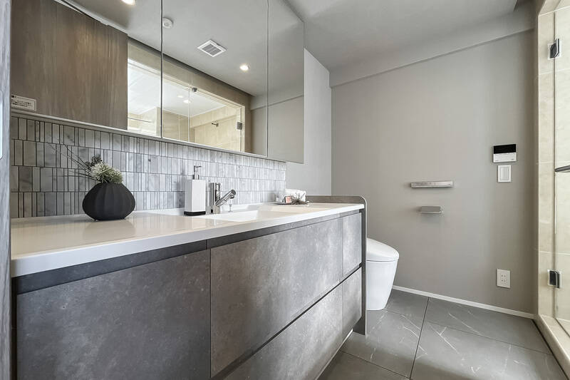 洗面台とトイレは2in1仕様。タイルや広い天板など、ホテルライクなデザインです。トイレはシンプルなタンクレスタイプ。ムダを排しており、お手入れがしやすそうな造りです。