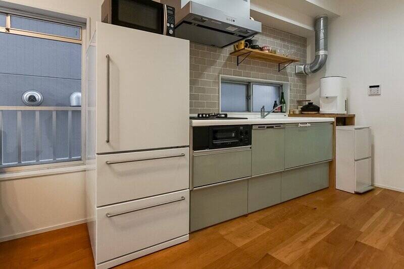 ミント色とグレーのタイルが可愛い2口コンロと食洗機が備わったキッチン。窓が付いており、お料理中に換気ができます◎