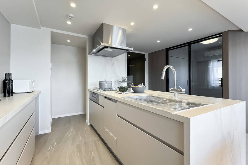 真っ白で清潔感のある、田中工藝社製のシステムキッチン。冷蔵庫置き場は壁の奥にあり、生活感が出にくくなっています。