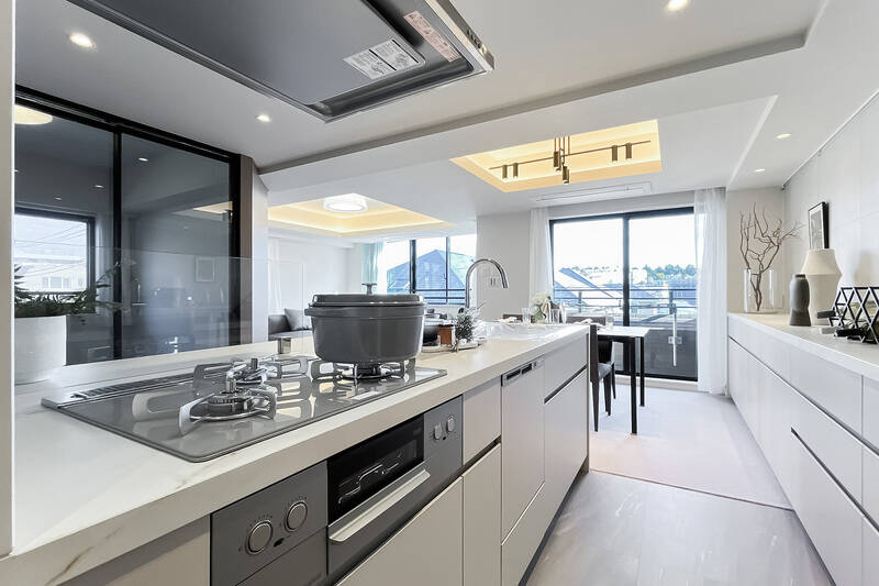 キッチン奥から見たLDK全景。お料理をしながら眺望をお楽しみいただけます。背面の収納カウンターは窓際まで続いており、食器やストック食品だけでなく、書類や文具までしまっていただけそう。