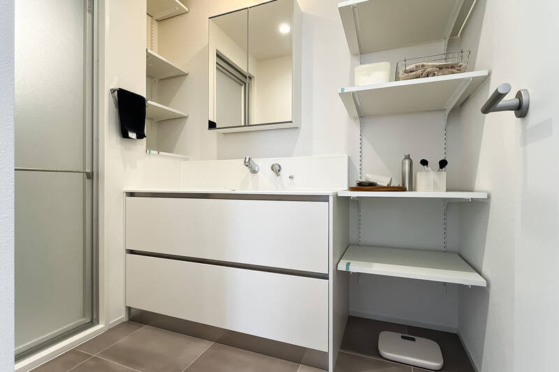 洗面脱衣室は洗濯機置き場をキッチン奥に出したことによって広々。可動棚が二箇所に設置されています。