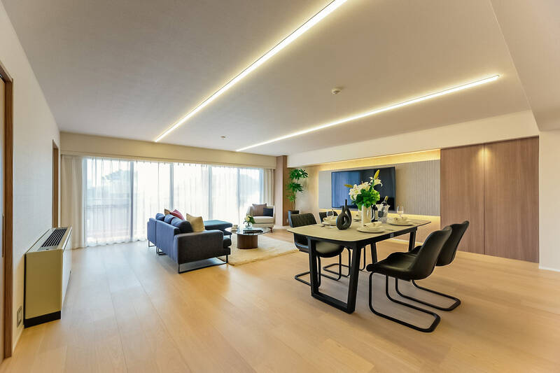 まずは約23.9帖のリビングダイニング（LD）からスタート。天井のラインライトや壁面の間接照明が上品です。薄手のカーテンを開けると……