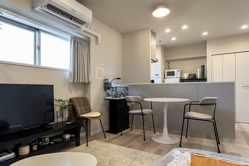 約11.5帖のLDK。壁とキッチンの腰壁がグレージュの色味で統一されており、落ち着いた印象です。