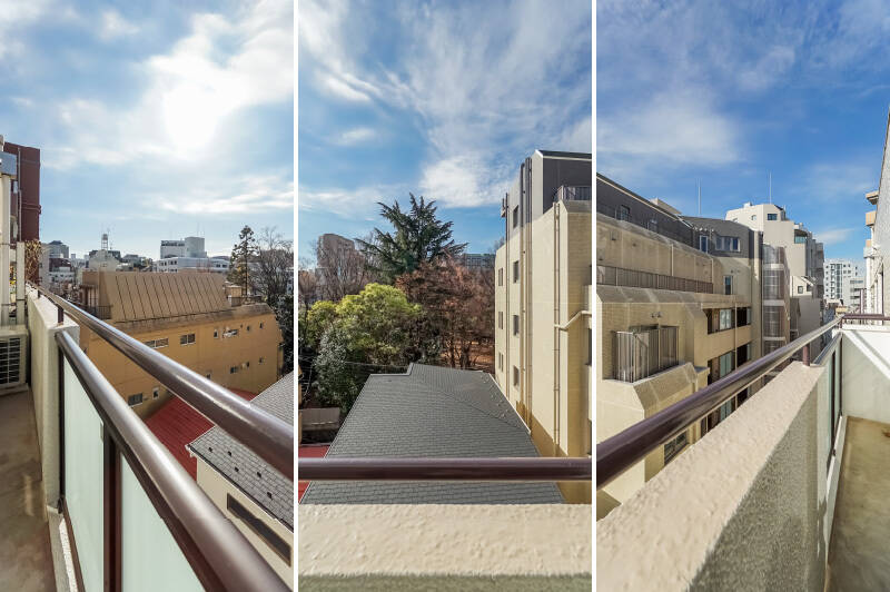 バルコニーは人ひとり立てる程度の浅い奥行きで、LDKの横幅いっぱいに延びています。現在地は地上5階。視界の上半分は大きな空、建物の合間には「占春園」の木々が見える気持ちのいいビューです。