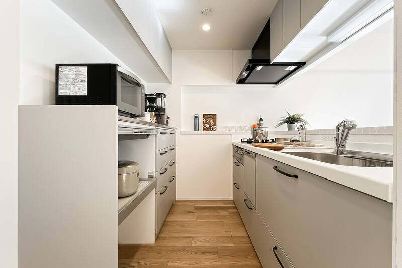 上下ともにたっぷりと収納が設けられたキッチン。カウンターのタイルは壁面までL字に配され、調味料などを置くのにぴったり。