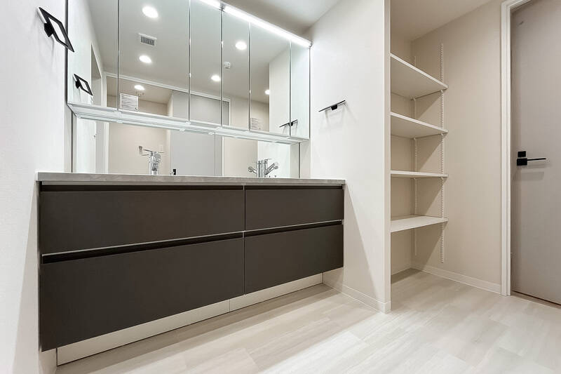 洗面化粧台はツーボウル式。引き出し収納に加え、横にはオープン棚も設置されています。