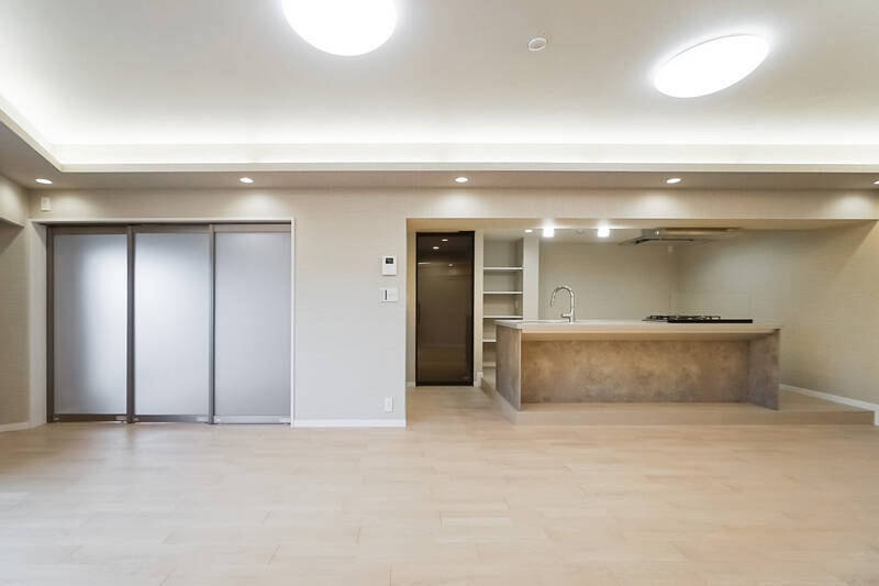 左手奥には、スモークガラスの引き戸で区切られた洋室Ａが。右手には、アイランドキッチンを中心としたキッチンエリアがあります。