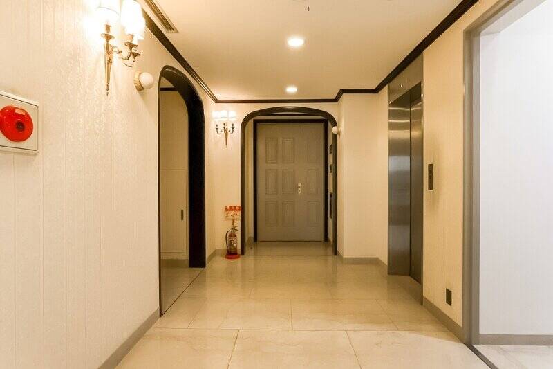 内廊下仕様の共用廊下は、アンティークのような灯りが点々と照らしています。各住戸の玄関前には、黒縁のアーチで飾られたアルコーブが。