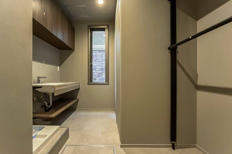 玄関近くにはいわゆる “家事室” が用意されています。洗濯機置き場、シンク、物干しまでひとつの空間にまとまっており、床には水に強い塩ビタイルが使われています。