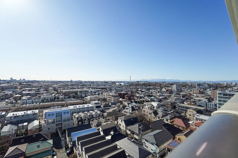 物件のバルコニーからこんにちは。カウカモです。ここは14階建てマンションの12階、南向きの住戸……説明不要の清々しい眺望をご覧ください！ 180度どこを向いても視界が開けているのですが、写真はやや右手に振って撮影しています。なぜかというと？