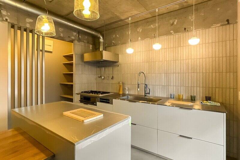 壁付けキッチンと作業カウンターの “Ⅱ型”。壁面のタイルやスチールのルーバーが内装テイストと絶妙にマッチしています。