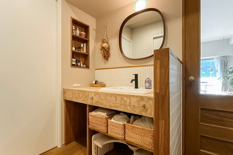 廊下から少し奥まったオープンな場所に設置された洗面化粧台。モールテックス仕上げのカウンター、細かなタイル使い、木の縁取りなど、どこも抜かりなくデザインされています。