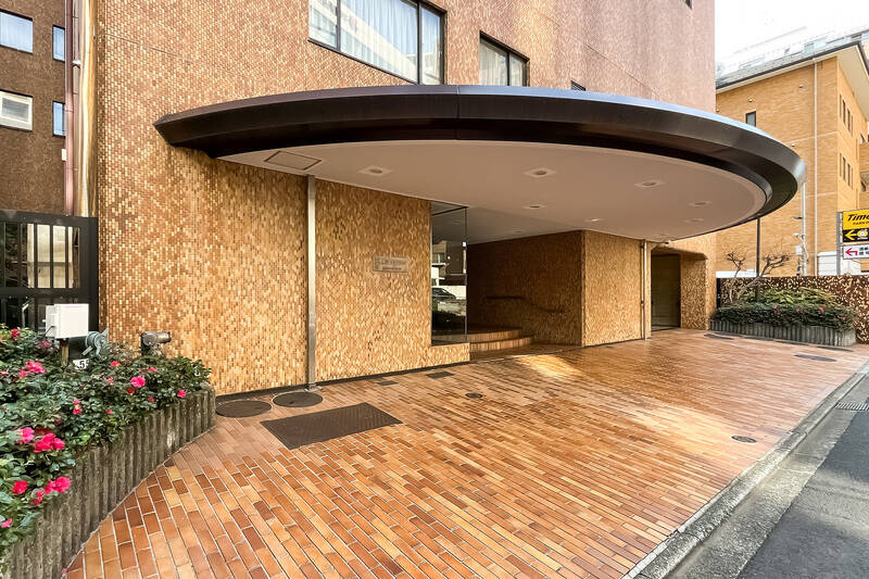 半円状の大きな庇がかかったエントランス。アーチを描くように配されたサザンカの花が彩りを添えています。