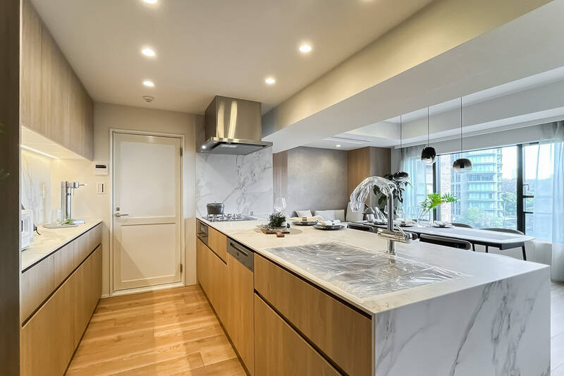 田中工芸製のシステムキッチンに、Miele製の大型食洗機を完備。背面には、たっぷりの収納力を備えたカップボードを設えています。突き当たりドアの中は機械室です。