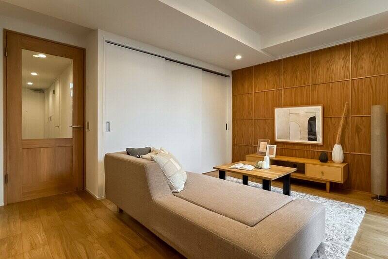 <p>リビングスペースの壁には木のパネルをあしらい、家族が自然と集まるような明るく温かみのある内装デザインに仕上げています。後ほどご紹介しますが、引き戸の先は洋室Bです。</p>