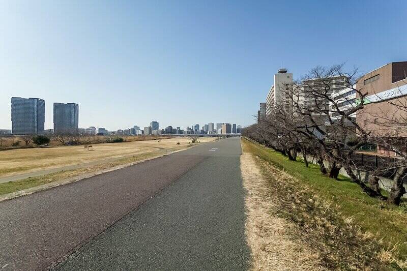 こちらは六郷水門近辺の多摩川の河川敷。春には満開の桜を楽しむことができます。開放感があって気持ちいい！ ここからマンションまでは徒歩4分の距離感。愛犬とお散歩をしたり、座ってのんびり読書をしたり、休日のプランが広がりますね。住戸からもリバービューを堪能できるので、後ほどご紹介する眺望をお楽しみに！