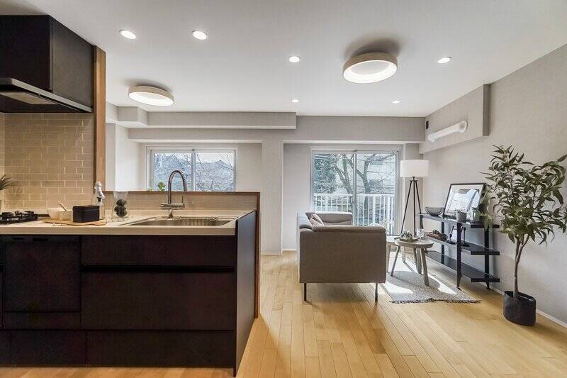 こちらは約14.2帖のLDK。ダークカラーのスタイリッシュなキッチンの向こうに、横に長い長方形のリビングダイニングが広がっています。