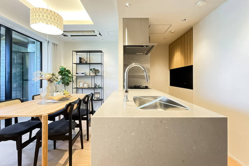 天板はお手入れがしやすく、ダイニングスペースへの料理のサーブもスムーズなフラットタイプです。キッチン背面には備え付けのカップボードがあり、調理家電やキッチンまわりの道具を収納できます。