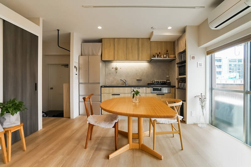 続いて、キッチン側を覗いてみましょう。全体的に木と白を基調とした空間に仕上がっています。キッチンや造り付けの収納が壁に沿ってプランされているので、すっきりとした印象。写真左手の扉の奥はサニタリールームです。