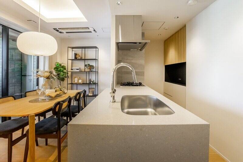 天板はお手入れがしやすく、ダイニングスペースへの料理のサーブもスムーズなフラットタイプです。キッチン背面には備え付けのカップボードがあり、調理家電やキッチンまわりの道具を収納できます。