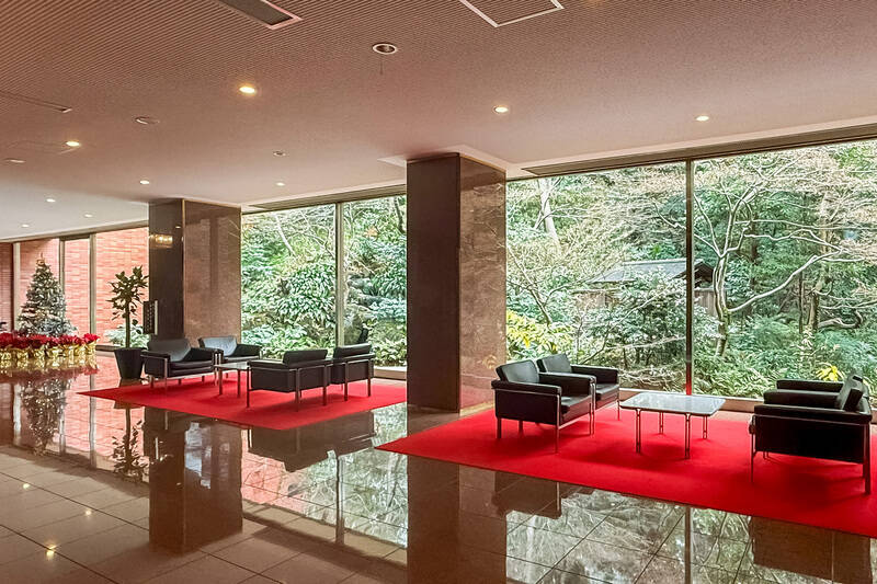大きなガラス張りの窓から、美しく手入れされた庭園の緑を望む共用ロビー。