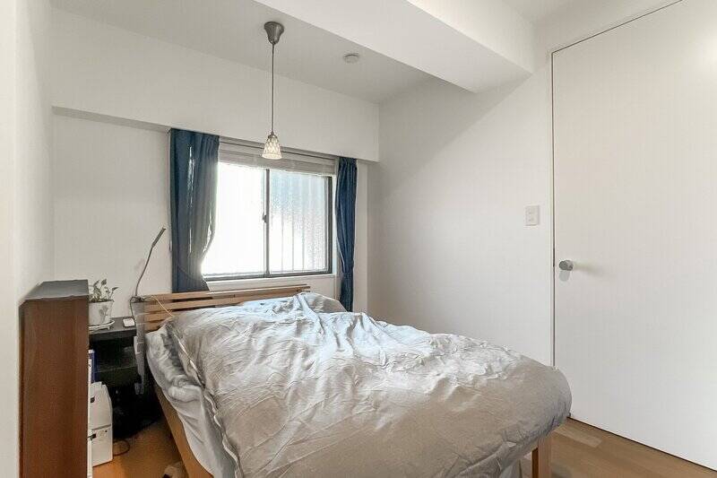 約5.1帖の洋室。ベッドと収納を無理なく配置できる、ちょうどいいサイズ感です。扉を出ると廊下へとつながります。