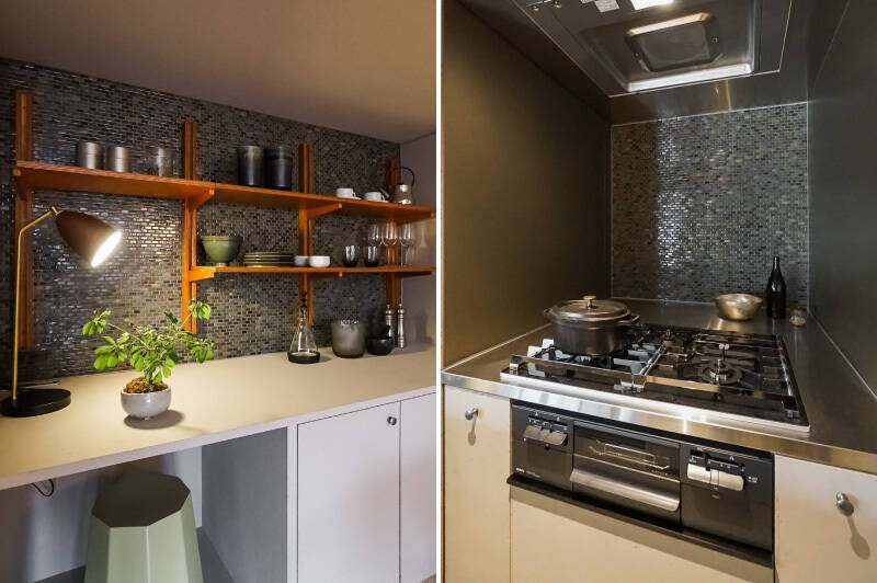 <b>左・</b>タイル壁×木製のウォールラックが可愛い作業カウンター。上部も下部も奥行きのある収納になっています◎/<b>右・</b>お揃いのタイルで仕上げたキッチンの熱源側には、全面五徳タイプの3口コンロを完備。とても奥行きが深いので、素材やお皿のちょい置きができて便利そう。