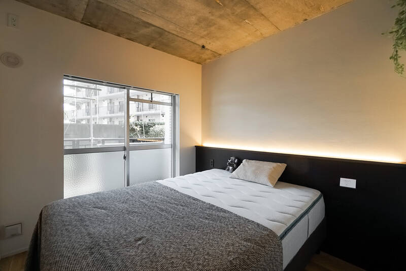 躯体現しになった天井がカッコいい洋室。間接照明を組み込んだヘッドボードが造作されているのもうれしいポイントです。夜の自分時間がもっと楽しみになりそう！