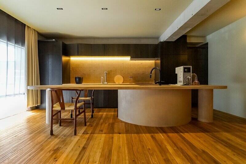 内装の主役とも言えるダイニングキッチン（DK）。楕円の天板や円柱はモールテックス仕上げで風合いがあり、背面は凹凸のあるタイルを収納が囲っています。