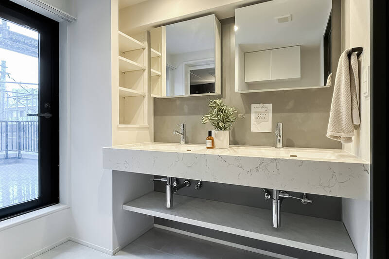 洗面台はツーボウルで広々。しかもここからルーフバルコニーに出られます！ 洗濯機置き場もこの空間にまとまっているため、お洗濯物はルーフバルコニーで干すのが家事効率上、便利かもしれません。