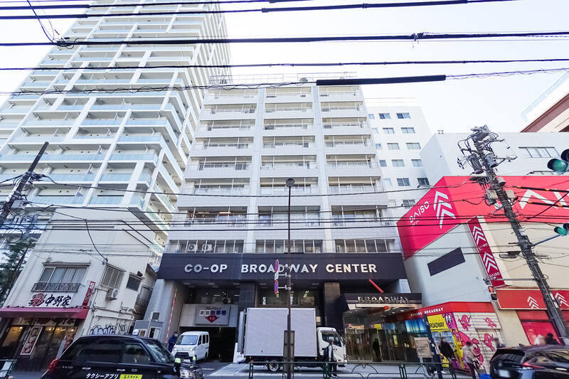 「中野」駅から続く商店街「中野サンモール」を抜けた先に現れる「中野ブロードウェイ」……なんと、今回の舞台はこちらの居住部分です！ “住む” というイメージが薄い「中野ブロードウェイ」ですが、早稲田通りから見上げると5階より上は居住部分なのがわかります。1966年に竣工した、総戸数251戸の大規模マンションです。