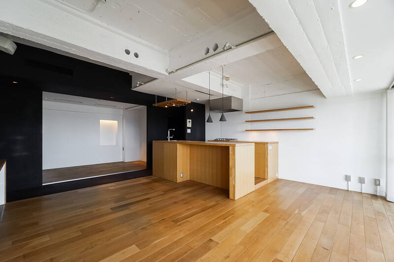 写真は、寝室（サービスルーム）の引き戸を開け放った状態です。それぞれの空間を隔てるL字型の廊下部分が、黒塗装＆黒カーペットで仕上げられているおかげで空間にメリハリがつき、寝室が闇にぽっかり浮いているよう。なんだか小劇場っぽくも見えますね。