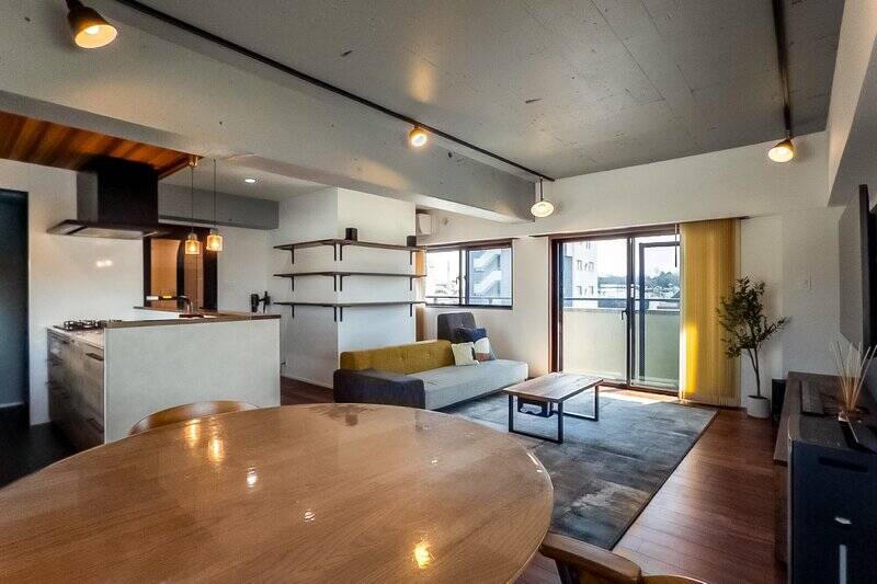 約24.2帖の広々としたLDK。天井は躯体現し、床は無垢ウォールナット張りになっており、素材感を楽しめるインダストリアルな空間に仕上がっています。