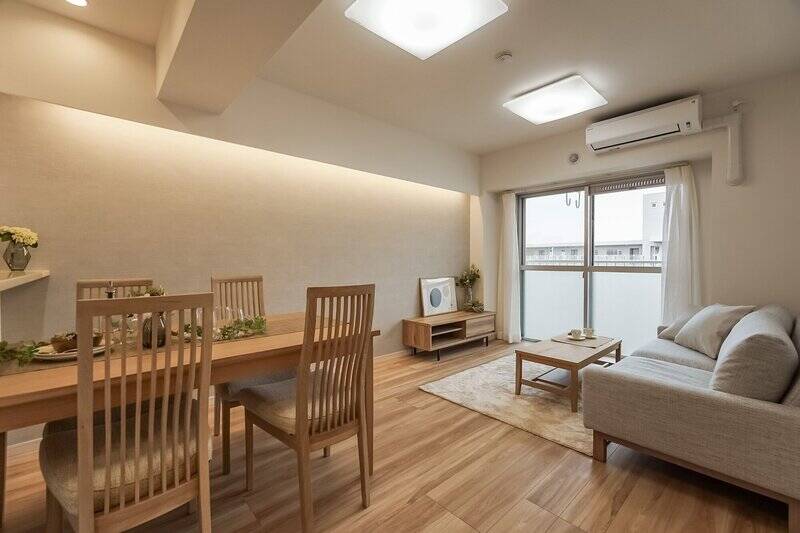 壁の間接照明がふんわりと優しい印象のLDK。広さは約13.4帖です。南側の大きな掃き出し窓のおかげで開放感があり、曇り空の日でも明るさを感じることができましたよ。